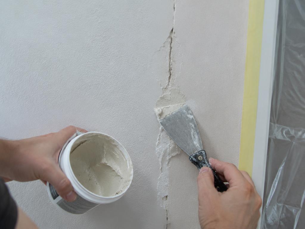 Reparação de fissura numa parede com espátula antes de pintar